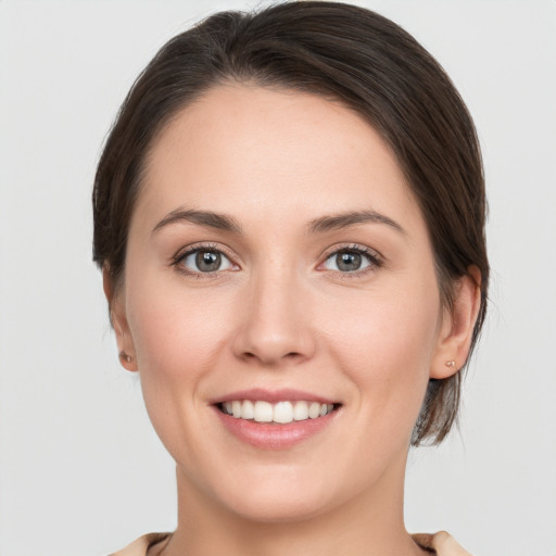 Joyful white young-adult female with medium  brown hair and grey eyes