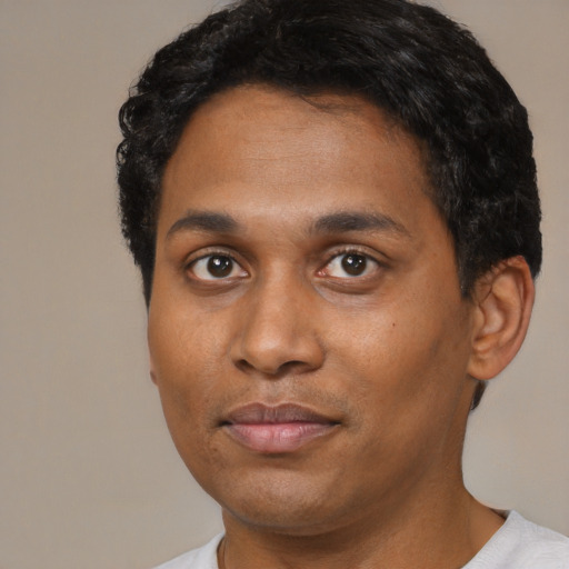 Joyful black young-adult male with short  black hair and brown eyes