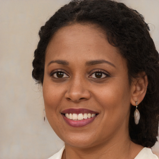 Joyful black young-adult female with long  brown hair and brown eyes