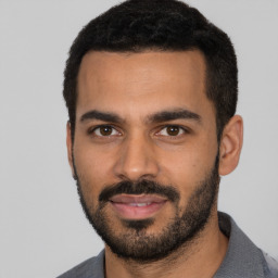 Joyful latino young-adult male with short  black hair and brown eyes