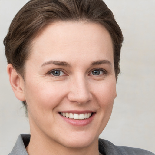 Joyful white young-adult female with short  brown hair and grey eyes