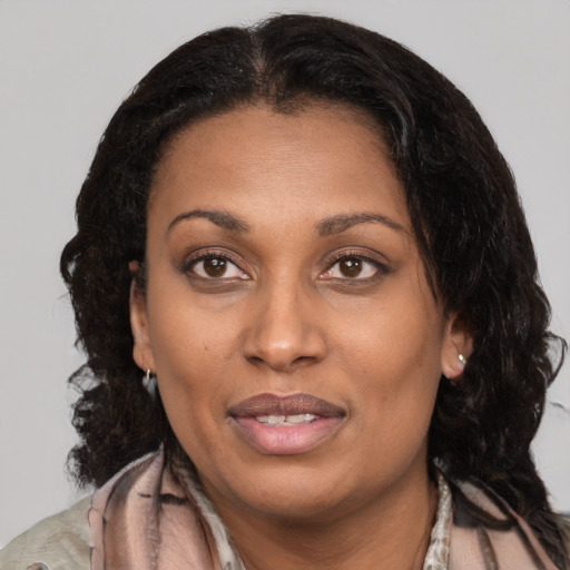 Joyful black adult female with long  brown hair and brown eyes