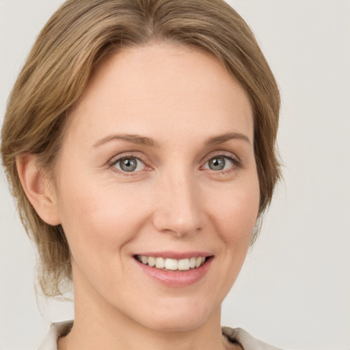 Joyful white young-adult female with medium  brown hair and grey eyes