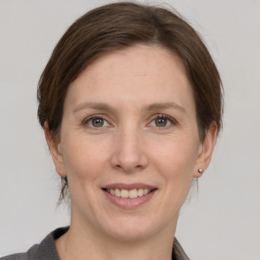 Joyful white young-adult female with medium  brown hair and grey eyes