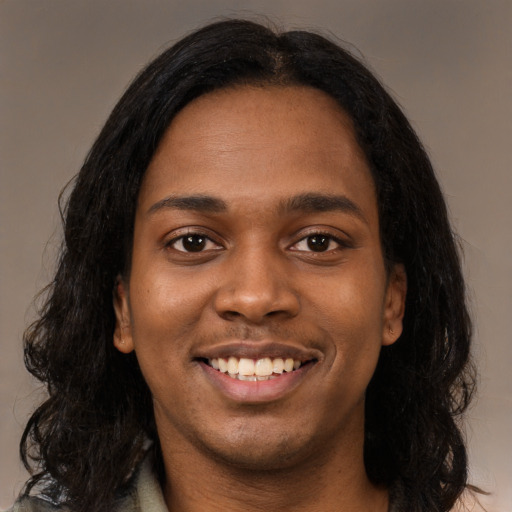 Joyful black young-adult female with long  black hair and brown eyes