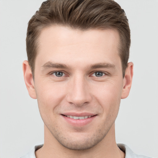 Joyful white young-adult male with short  brown hair and grey eyes