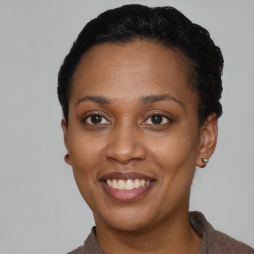 Joyful black young-adult female with short  black hair and brown eyes