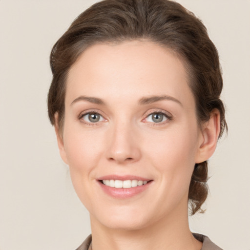 Joyful white young-adult female with medium  brown hair and grey eyes