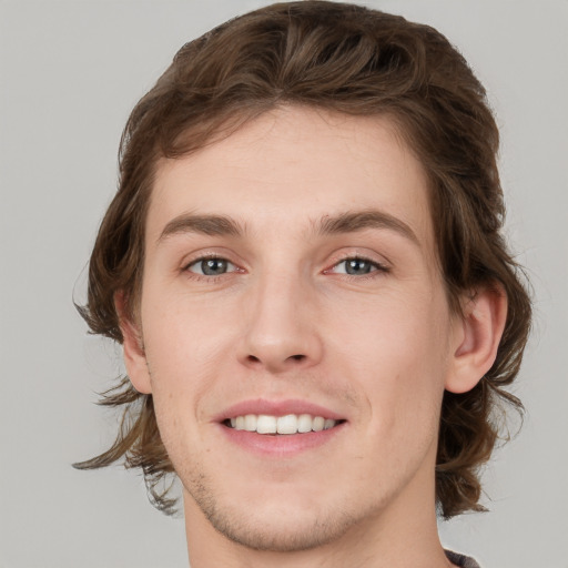 Joyful white young-adult male with medium  brown hair and grey eyes