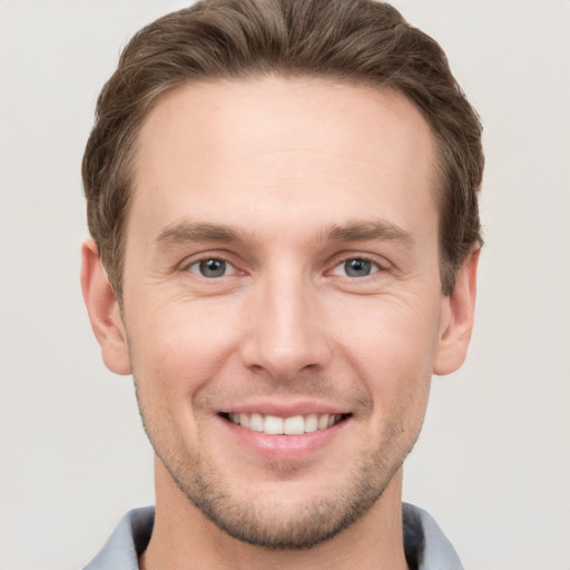 Joyful white young-adult male with short  brown hair and grey eyes