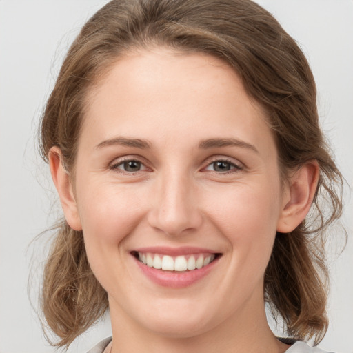 Joyful white young-adult female with medium  brown hair and grey eyes