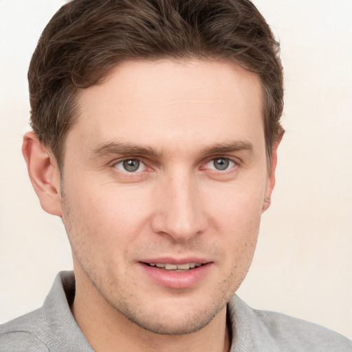 Joyful white young-adult male with short  brown hair and grey eyes