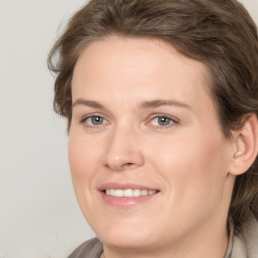 Joyful white young-adult female with medium  brown hair and grey eyes