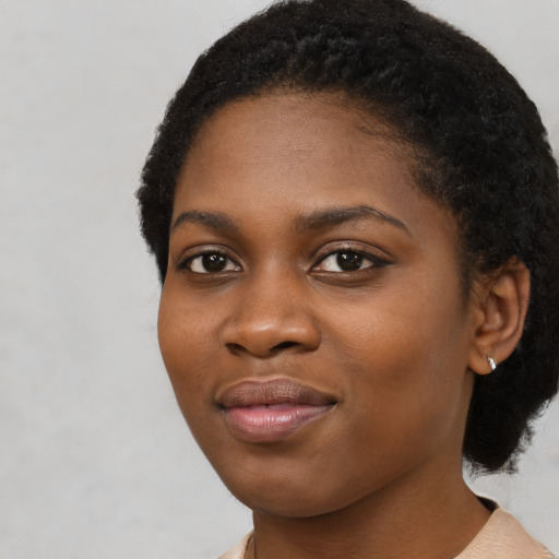 Joyful black young-adult female with short  black hair and brown eyes