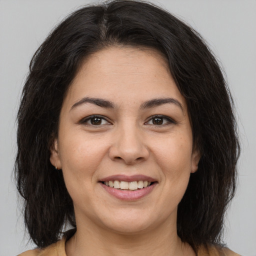 Joyful latino young-adult female with medium  brown hair and brown eyes