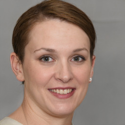 Joyful white young-adult female with short  brown hair and grey eyes