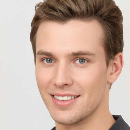 Joyful white young-adult male with short  brown hair and grey eyes