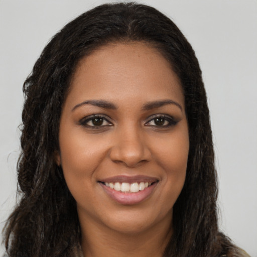 Joyful black young-adult female with long  brown hair and brown eyes