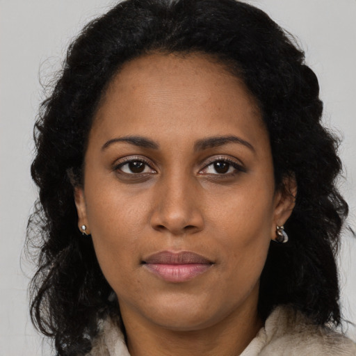 Joyful black adult female with long  brown hair and brown eyes