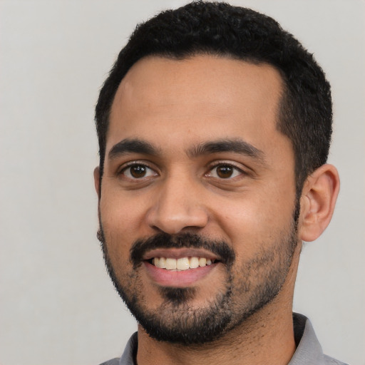 Joyful latino young-adult male with short  black hair and brown eyes