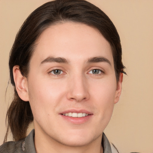 Joyful white young-adult male with long  brown hair and brown eyes