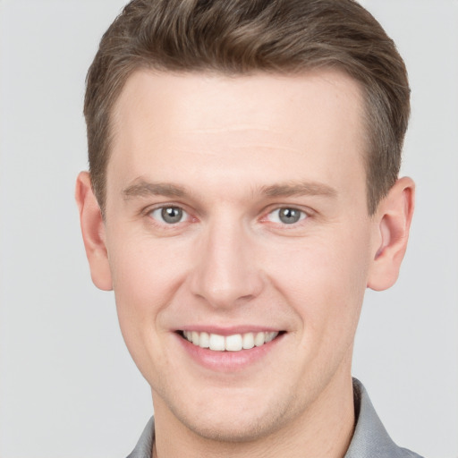 Joyful white young-adult male with short  brown hair and grey eyes