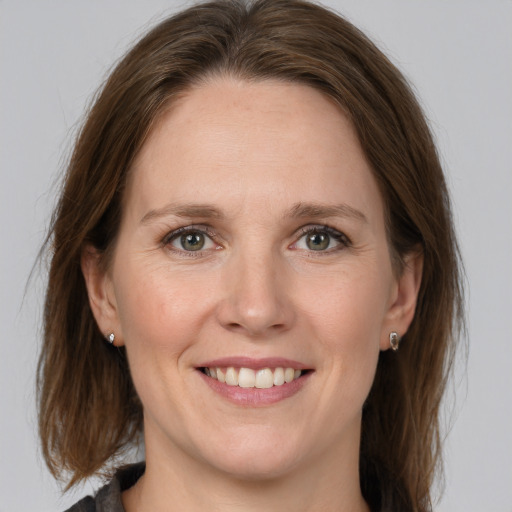 Joyful white adult female with medium  brown hair and grey eyes