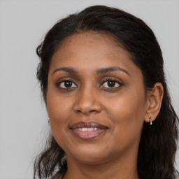 Joyful black adult female with long  brown hair and brown eyes