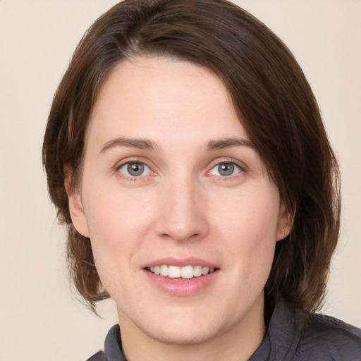 Joyful white young-adult female with medium  brown hair and grey eyes