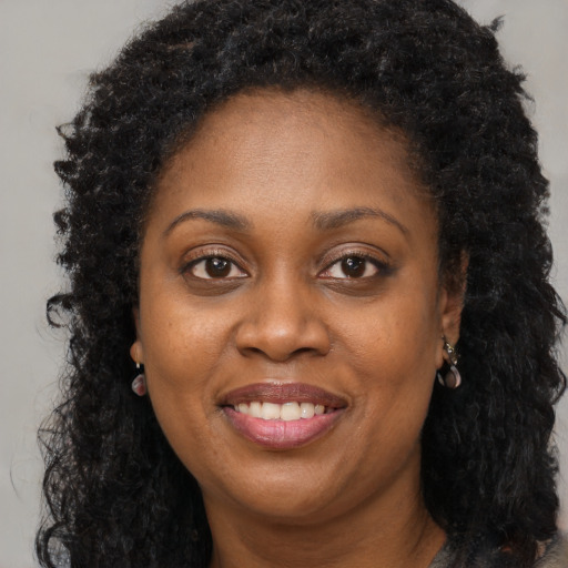 Joyful black adult female with long  brown hair and brown eyes