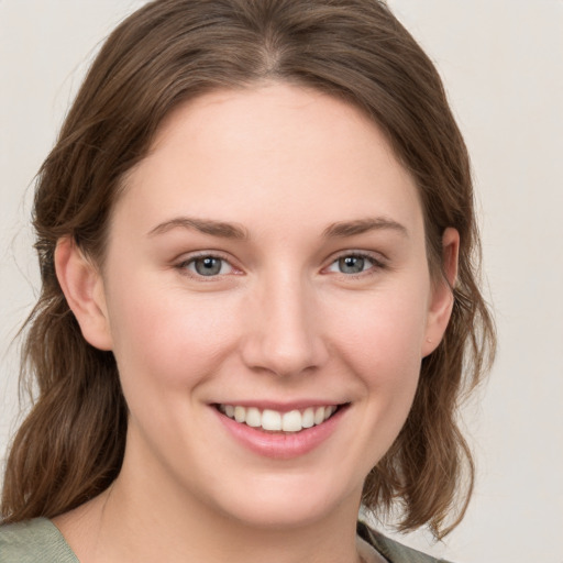 Joyful white young-adult female with medium  brown hair and grey eyes