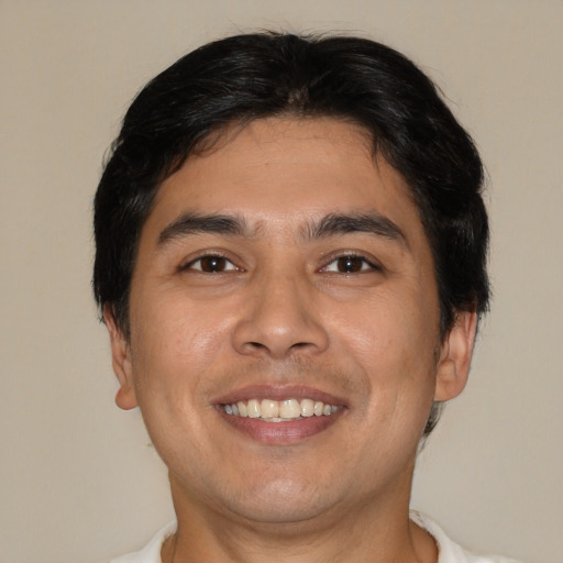 Joyful latino young-adult male with short  brown hair and brown eyes