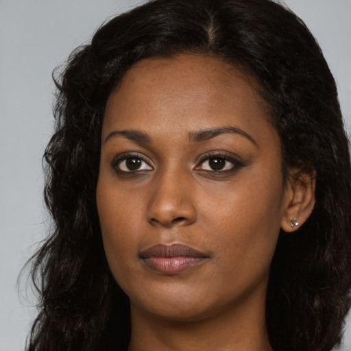 Joyful black young-adult female with long  brown hair and brown eyes
