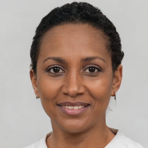 Joyful black young-adult female with short  black hair and brown eyes