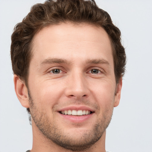 Joyful white young-adult male with short  brown hair and grey eyes