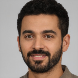 Joyful latino young-adult male with short  black hair and brown eyes