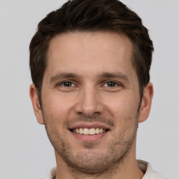 Joyful white young-adult male with short  brown hair and grey eyes