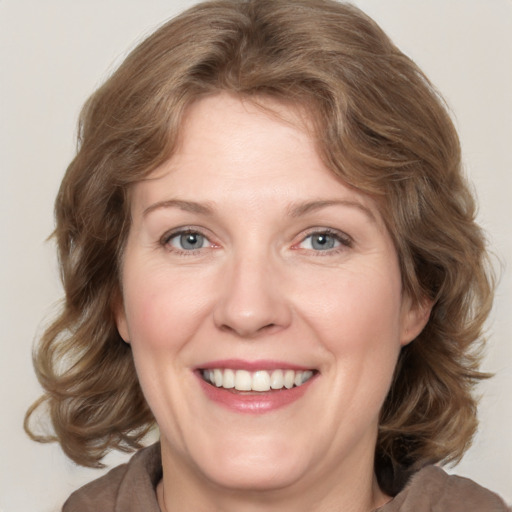 Joyful white adult female with medium  brown hair and grey eyes