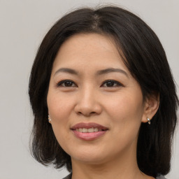 Joyful asian adult female with medium  brown hair and brown eyes