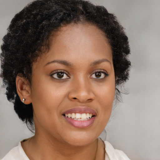 Joyful black young-adult female with long  brown hair and brown eyes