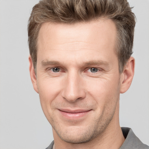 Joyful white adult male with short  brown hair and grey eyes