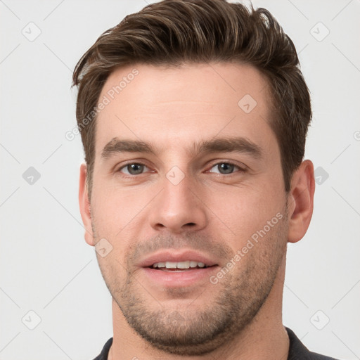 Joyful white young-adult male with short  brown hair and grey eyes