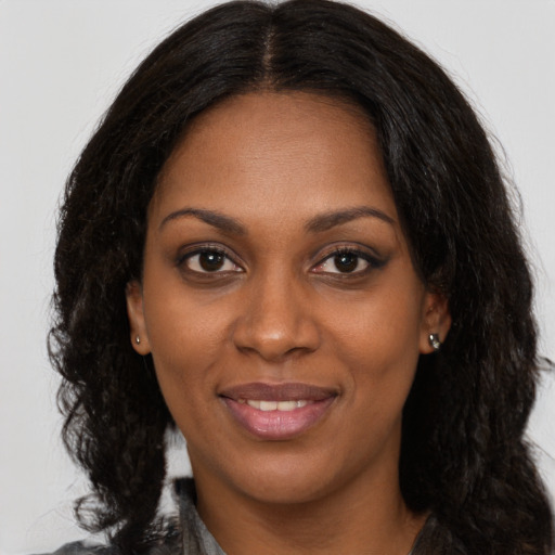 Joyful black young-adult female with long  brown hair and brown eyes
