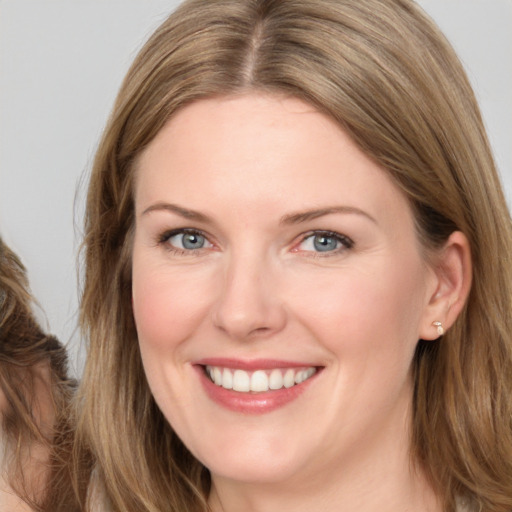 Joyful white young-adult female with long  brown hair and blue eyes