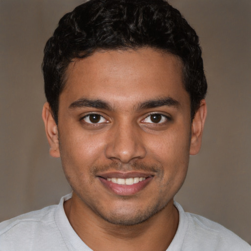 Joyful black young-adult male with short  brown hair and brown eyes