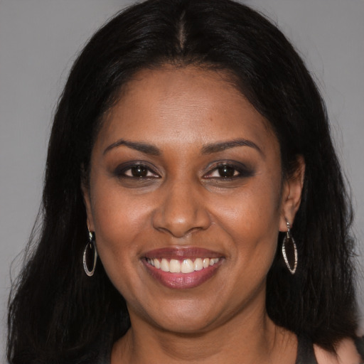 Joyful black young-adult female with long  brown hair and brown eyes
