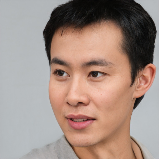 Joyful asian young-adult male with short  black hair and brown eyes