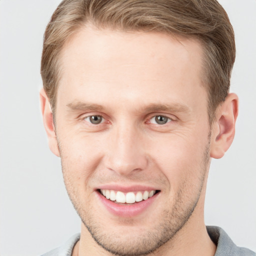 Joyful white young-adult male with short  brown hair and grey eyes