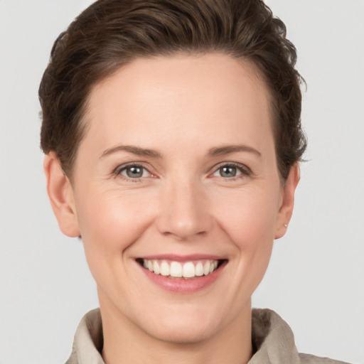 Joyful white young-adult female with short  brown hair and grey eyes