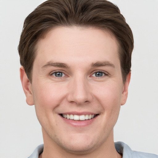 Joyful white young-adult male with short  brown hair and grey eyes